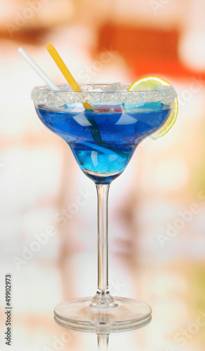Photo: Blue cocktail in glass on room background Blue cocktail in glass on room background