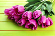 Beautiful bouquet of purple tulips on green wooden background