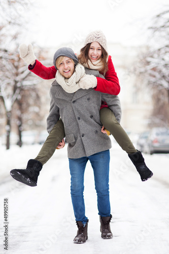 Photo: Man giving woman piggyback in winter setting Man giving woman piggyback in winter setting