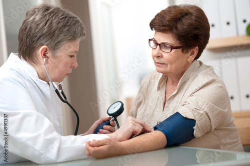 Photo: doctor measuring blood pressure of female patient doctor measuring blood pressure of female patient
