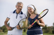 Mature couple holding tennis racquets