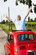 Mature man enjoying a road trip in a small red car