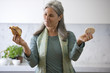 Mature woman deciding between croissant and a rice cake