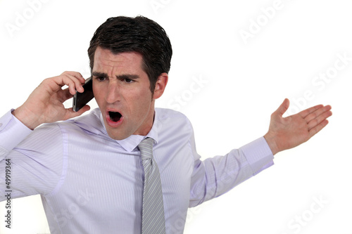Photo: angry businessman talking on his cell angry businessman talking on his cell