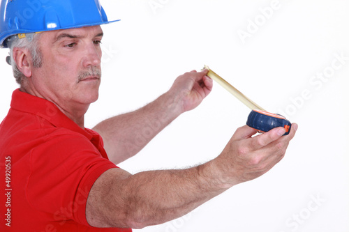 Photo: Middle-aged handyman using tape-measure Middle-aged handyman using tape-measure