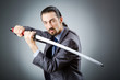 Angry businessman with sword in dark room