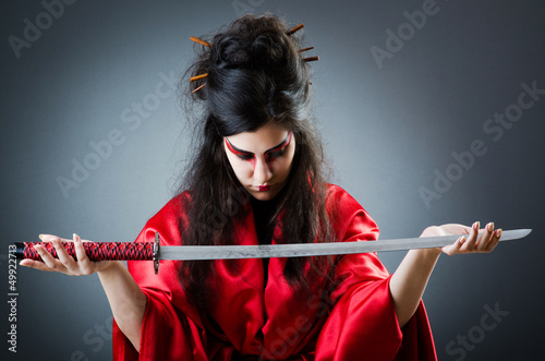 Photo: Female sword warriod in dark studio Female sword warriod in dark studio