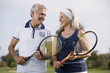 Mature couple holding tennis racquets