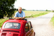 Mature man enjoying a road trip in a small red car
