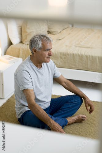 Photo: Mature man doing yoga in bedroom Mature man doing yoga in bedroom