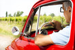 Mature man enjoying a road trip in a small red car