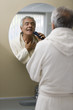 Mature man shaving in bathroom mirror