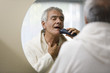 Mature man shaving in bathroom mirror