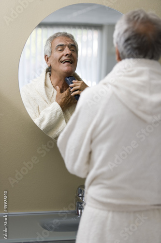 Photo: Mature man shaving in bathroom mirror Mature man shaving in bathroom mirror