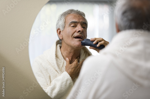 Photo: Mature man shaving in bathroom mirror Mature man shaving in bathroom mirror