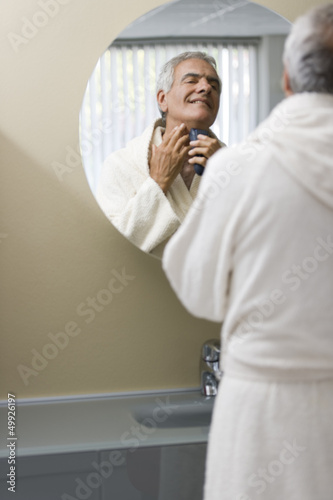 Photo: Mature man shaving in bathroom mirror Mature man shaving in bathroom mirror
