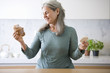 Mature woman deciding between croissant and a rice cake