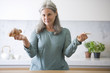 Mature woman deciding between croissant and rice cake