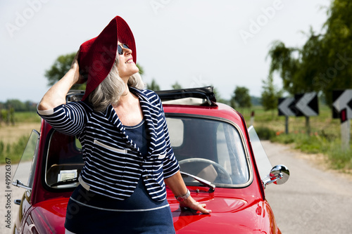 Photo: Mature woman enjoying a road trip in a small red car Mature woman enjoying a road trip in a small red car