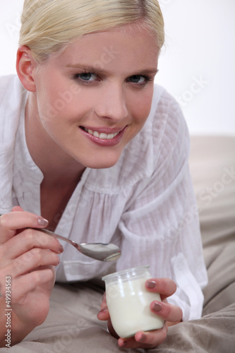 Photo: Woman eating yogurt in bed Woman eating yogurt in bed