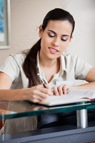 Photo: Female Receptionist Writing In Book Female Receptionist Writing In Book