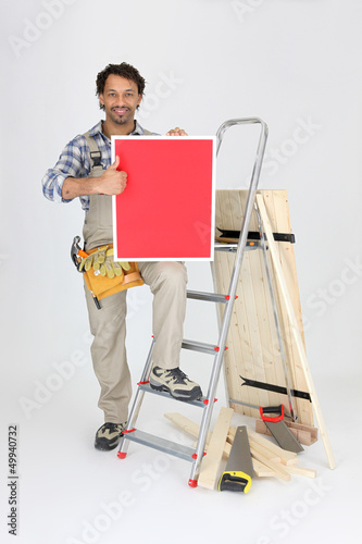 Photo: Carpenter with a board left blank for your message Carpenter with a board left blank for your message