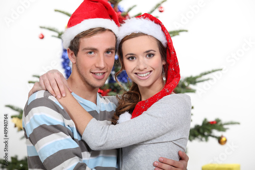 Photo: Young couple hugging by Christmas tree Young couple hugging by Christmas tree