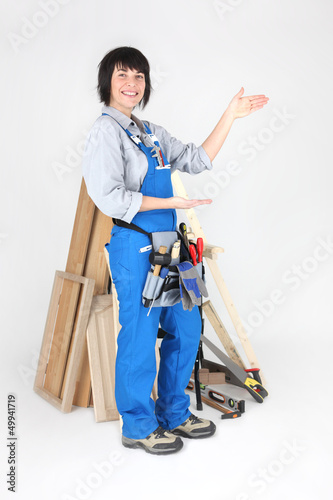 Photo: Female carpenter indicating the space to her side Female carpenter indicating the space to her side