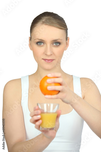 Photo: young woman pressing an orange young woman pressing an orange