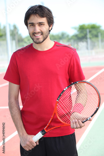 Photo: Casual tennis player standing on a hard court Casual tennis player standing on a hard court