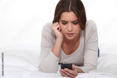 Photo: Woman reading disturbing text message Woman reading disturbing text message