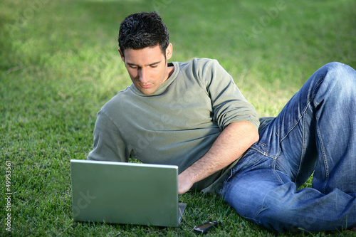 Photo: Man with laptop laying in field Man with laptop laying in field