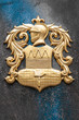 Gold arms with knight image on granite wall.