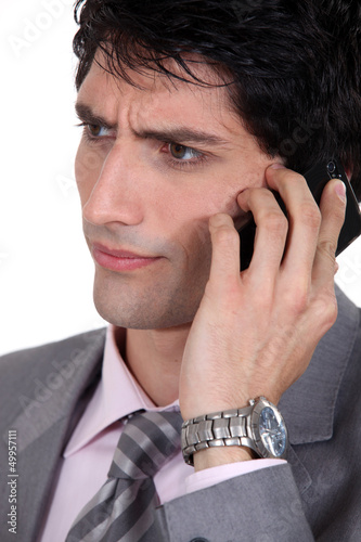 Photo: Frowning businessman using a cellphone Frowning businessman using a cellphone