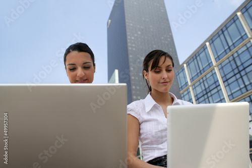 Photo: two young businesswomen working on their laptops two young businesswomen working on their laptops
