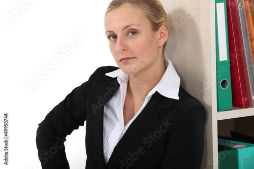 Photo: Businesswoman leaning against bookshelf Businesswoman leaning against bookshelf