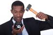 Man in a suit hammering open a child's piggy bank