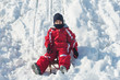 Kid sliding with sled in the snow.