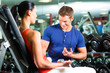woman and Personal Trainer in gym with dumbbells
