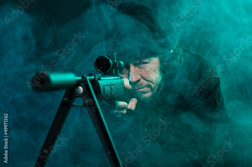 Photo: Sniper with beard in black holding gun. Studio shot. Sniper with beard in black holding gun. Studio shot.