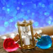 Foto: Sanduhr mit bunten Fläschchen und Bokeh-effekt Sanduhr mit bunten Fläschchen und Bokeh-effekt