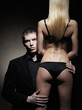 Face of a young man looking behind the back of a sexy woman