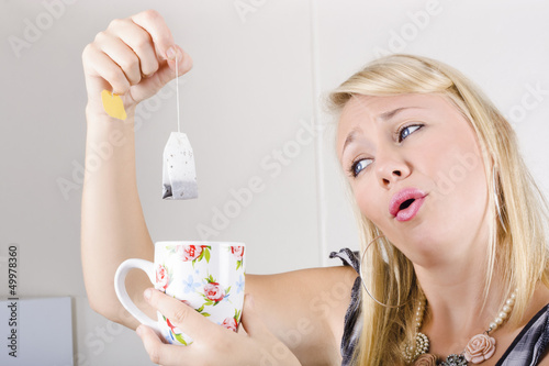 Photo: Worker with look of relief holding tea bag and cup Worker with look of relief holding tea bag and cup