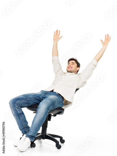 Photo: happy man sits on the chair and raised hands up happy man sits on the chair and raised hands up