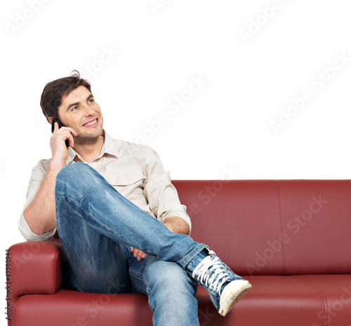 Photo: man sits on the divan and speaks on mobile phone man sits on the divan and speaks on mobile phone