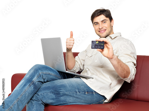 Photo: man with laptop shows the credit card man with laptop shows the credit card