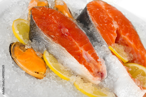Photo: Pieces of red fish on ice in plate isolated on white Pieces of red fish on ice in plate isolated on white