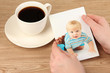 Photo in hands and cup of coffee on wooden table