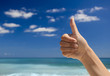 Thumbs up against a blue sky
