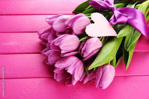 Photo: Beautiful bouquet of purple tulips on pink wooden background Beautiful bouquet of purple tulips on pink wooden background